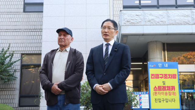 15일 창원지방법원 법정동 앞에서 재심 사건 전문 박준영(오른쪽) 변호사가 취재진 질문에 답하고 있다. 왼쪽은 이날 창원 택시기사 살인 사건 재심 개시 결정을 선고받은 보조로브 아크말 씨의 아버지. 최환석 기자